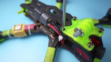 Close up of a hand screwdriver male craftsman unscrewing a fpv self-assembled drone on his desk. Shallow depth of field. Unscrewing and screwing video
