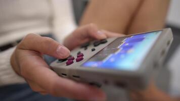 Close-up in shallow depth of field. Unrecognizable portable retro console in hands of young Caucasian woman. Girl plays retro games holding retro device for emulating old console games video
