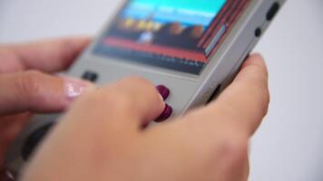 Close-up in shallow depth of field. Unrecognizable portable retro console in hands of young Caucasian woman. Girl plays retro games holding retro device for emulating old console games video
