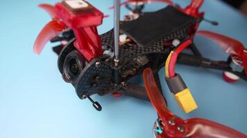 Close-up of diy drone on blue desktop. Disassembling and repairing drone at home. Hex screwdriver unscrews carbon frame of self-assembled fpv quadcopter video