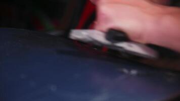 Female hands of a snowboard repairman cleaning wax off the sliding surface of a snowboard. Close-up with shallow depth of field. Low key video