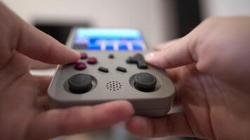 Close-up in shallow depth of field. Unrecognizable portable retro console in hands of young Caucasian woman. Girl plays retro games holding retro device for emulating old console games video