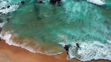 Drone view of serene ocean waves moving towards shore through rocks video