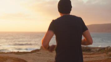 Athletic man jogging running on ocean beach at sunset background video