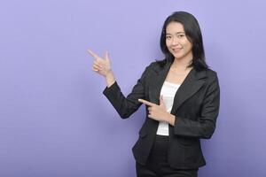Asian business woman pointing at something on purple background photo
