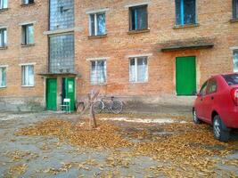 A quiet autumn afternoon in a quaint neighborhood with bicycles and fallen leaves near a rustic brick building photo