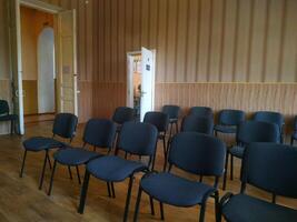 A quiet, organized room with rows of chairs awaiting participants in a collaborative meeting or workshop setting during daytime hours photo