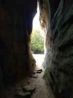 Exploring a sunlit crevice in nature's rock formations under a clear sky photo