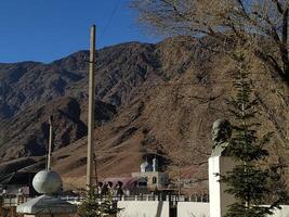 A tranquil afternoon view of imposing mountains framed by trees and historic statues in a remote village photo