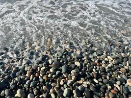 Gentle ocean waves lapping against a colorful pebble shore creating a serene coastal atmosphere photo