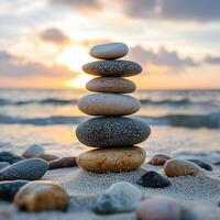 Balanced stones on sandy beach at sunset with calm ocean waves and soft golden light creating a peaceful scene photo