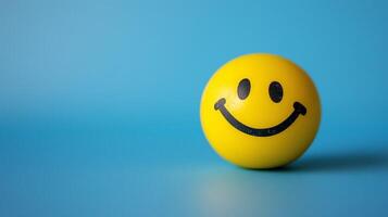 Minimalistic yellow smiley face ball on blue background symbolizing happiness and positivity in a simple design photo