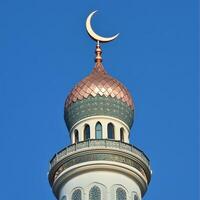 Beautiful mosque minaret topped with a crescent moon against a clear blue sky, showcasing Islamic architecture photo