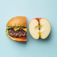 Creative composition of a hamburger and an apple half on a light blue background contrasting fast food and healthy eating photo