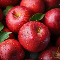Fresh red apples with water droplets and green leaves in a close-up display of vibrant and natural produce photo