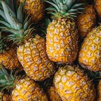 A pile of fresh whole pineapples with vibrant yellow skins and green leaves, showcasing tropical abundance photo