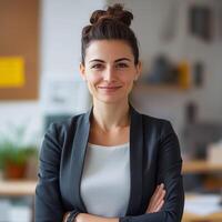 Confident professional woman in a business suit smiling with arms crossed in a modern office environment photo
