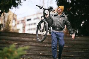 Man Carrying Bicycle Down Steps in Urban Park photo