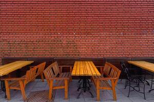 Wooden tables and chairs against a background of a red brick wall. photo