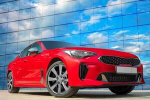 Red car on a blue sky background with white clouds. A stylish, modern, bright image of an avto mobile for design solutions. photo