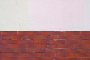 Half of the red brick wall is painted over with white plaster. Abstract construction background. photo