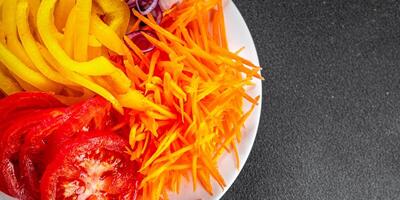 salad fresh vegetables cut into a plate tomato, carrot, pepper, onion juicy fresh gourmet food background on the table rustic food top view copy space keto and paleo diet Vegetarian and vegan photo