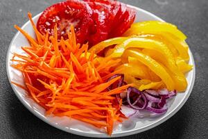 salad fresh vegetables cut into a plate tomato, carrot, pepper, onion juicy fresh gourmet food background on the table rustic food top view copy space keto and paleo diet Vegetarian and vegan photo