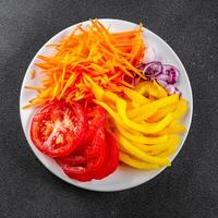 salad fresh vegetables cut into a plate tomato, carrot, pepper, onion juicy fresh gourmet food background on the table rustic food top view copy space keto and paleo diet Vegetarian and vegan photo