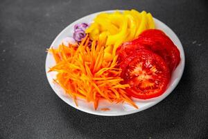 salad fresh vegetables cut into a plate tomato, carrot, pepper, onion juicy fresh gourmet food background on the table rustic food top view copy space keto and paleo diet Vegetarian and vegan photo