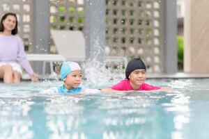 Asian kids girl and mom playing and having fun in swimming pool, Asian children in swimsuit playing in swimming pool photo