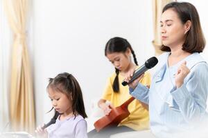 Mother with daughter relaxing together in living room, Asian mom enjoying with child while singing and playing the guitar in living room at home photo
