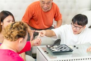 Asian friends playing a game of checkers at home, Senior man with grandchild relaxing together at home photo