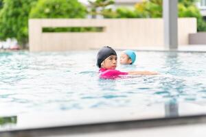 Asian children in swimsuit playing in swimming pool, Asian kids girl playing and having fun in swimming pool photo
