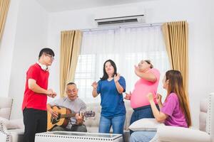 Senior man and grandchild having fun together while singing and playing the guitar in living room at home photo