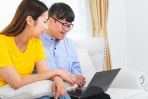 A group of friends using laptop doing a call in living room, Young man and woman sitting on sofa and using a laptop photo