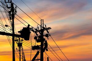 Silhouette of Electrician officer climbs a pole and uses a cable car to maintain a high voltage line system, Shadow of Electrician lineman repairman worker at climbing work on electric post power pole photo