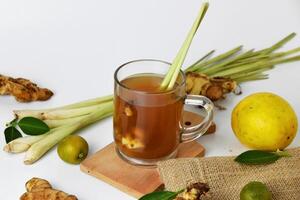 Hot red ginger drink in a glass cup with some raw ginger with white background photo