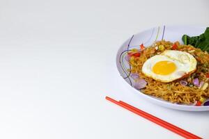 Fried noodles with sunny side up egg and mixed vegetables on a plate photo