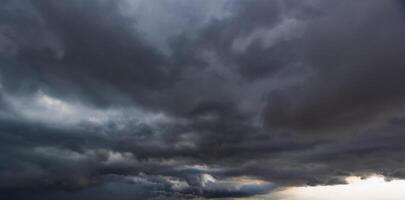 The dark sky with heavy clouds converging and a violent storm before the rain.Bad or moody weather sky and environment. carbon dioxide emissions, greenhouse effect, global warming, climate change. photo