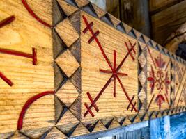 A close-up of traditional wooden carving featuring geometric patterns painted in red. The intricate design showcases the craftsmanship and cultural significance of rural artistry photo