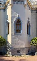 A series of pointed arched Gothic windows framed in gold with intricate lattice patterns adorn the exterior of a historic building. Captured in natural daylight, the windows reflect the surrounding photo