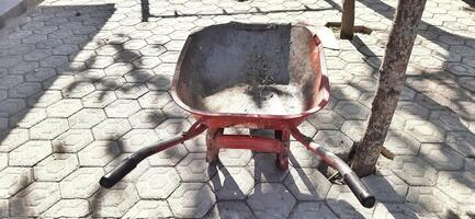 Dirty red cart or wheelbarrow for construction work photo