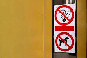 Signs prohibiting smoking and entry into building with dogs. Restricted area with no access for pets. Crossed out cigarette and dog on sticker on building door photo