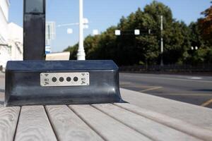 Bench with built in USB connectors for charging mobile devices and accurate Wi-Fi access. Modern public transport stop in metropolis street with bench for waiting bus and charging phone photo