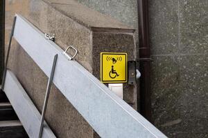 Yellow icon with call button for the disabled people for lifting, convenience for wheelchair users while walking in city, folding ramp for disabled people on narrow stairs photo