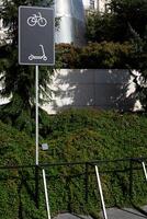Special area with metal structure for securing bicycles and scooters in park next to sign indicating the parking area for personal mobile vehicles with locker photo