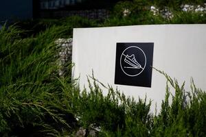 Sticker with crossed out sneaker on wall of decorative structure in public park, prohibition of stepping on surface in park, cleanliness and care photo