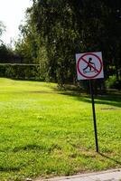 Sign in the park prohibits riding scooter. Road sign regulating traffic on city street. Modern rules for scooters in green field background photo