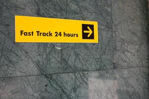 Sign on the wall indicating the direction of travel to access the fast track, convenient guide on wall of building when traveling photo
