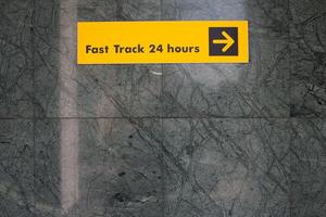 Sign on wall that says Fast Track 24 Hours and arrow for way. Sign to help guide you in an unfamiliar place for travelers on wall photo